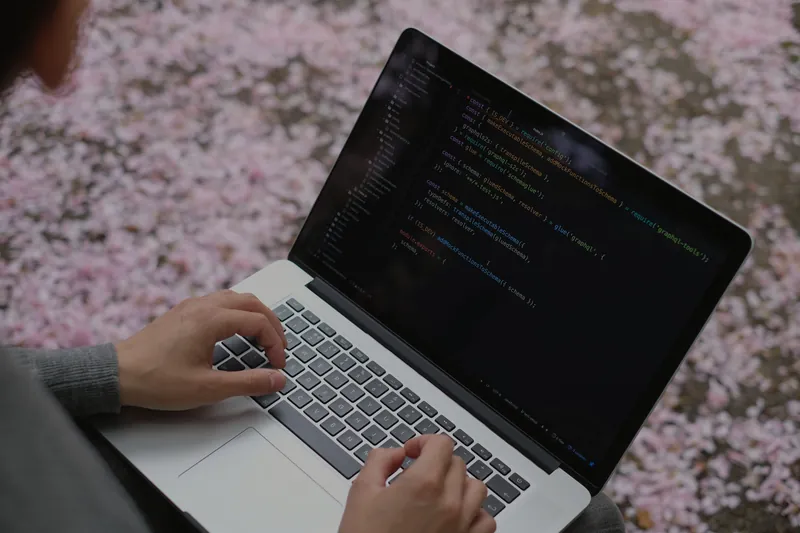 Hände auf einem Laptop mit Programmcode als Symbol für das IT-Strafrecht